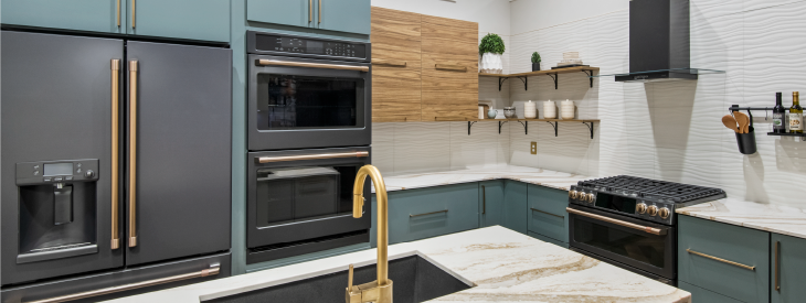 Sleek kitchen featuring matte teal lower cabinets, natural wood upper shelves, stainless steel appliances, white textured backsplash, and marble countertops.